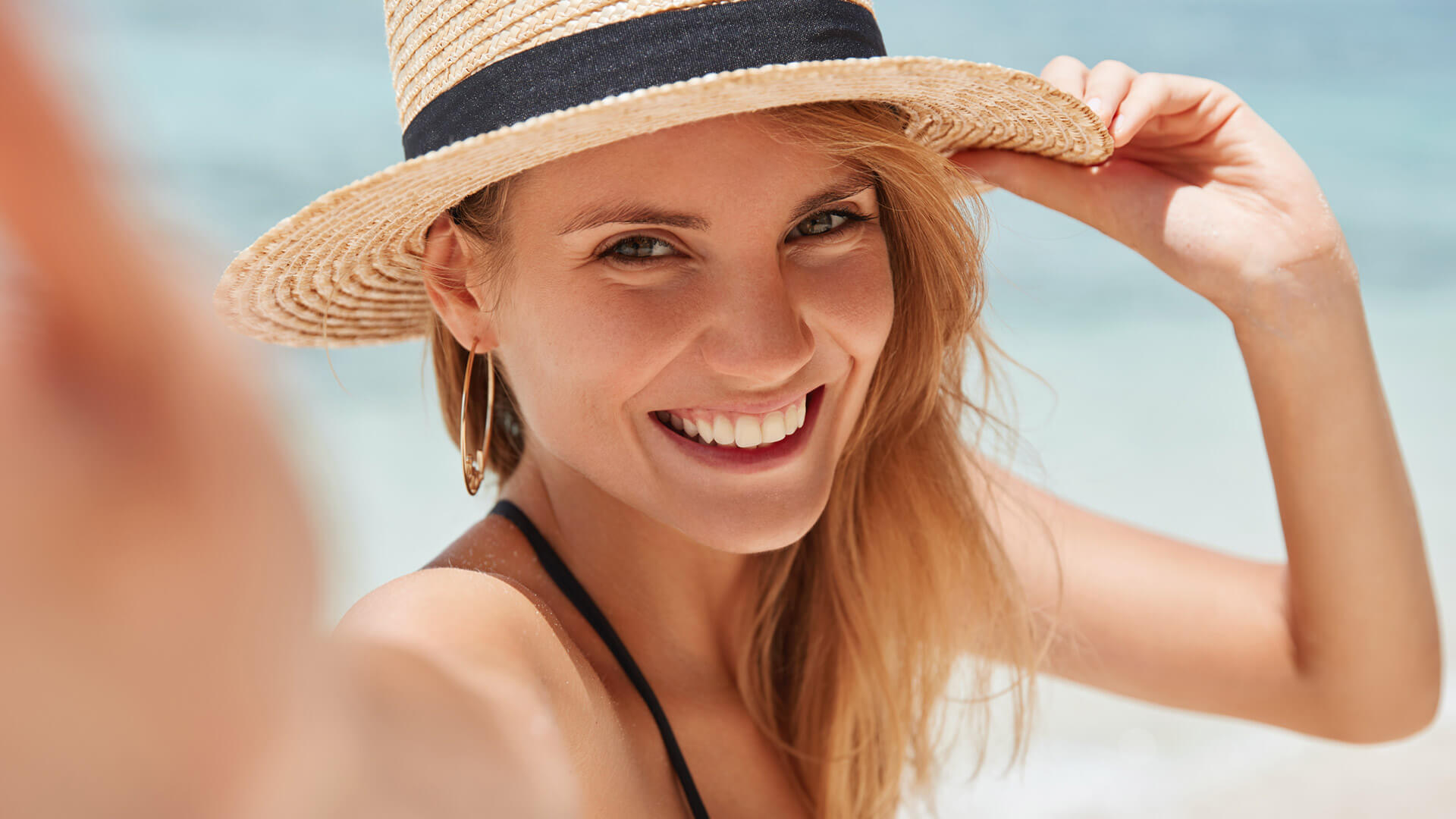 woman smiling at beach wearing hat